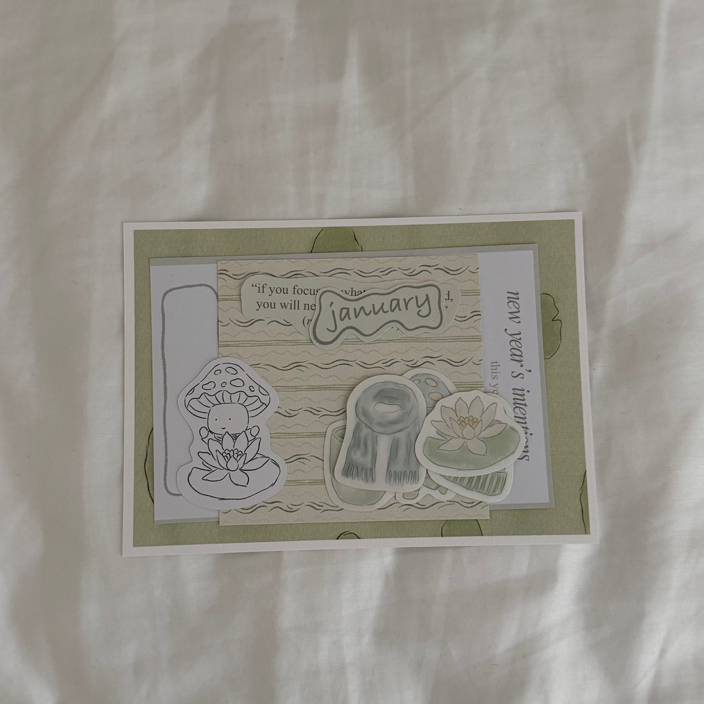 Inside an open envelope: 5x7 water lily print, 4x4 matching patterned print in soft sage green tones, five matte stickers, journal and activity prompts, a mini mushroom coloring card