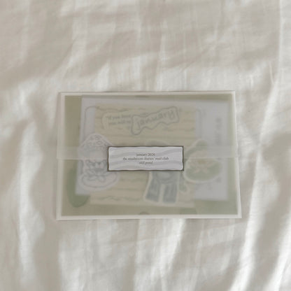Envelope containing a 5x7 water lily art print, a 4x4 matching dainty patterned art print in soft sage green tones, five matte vinyl stickers, journal prompts, an activity card, a mini coloring card of a mushroom character (marker bleed-safe).