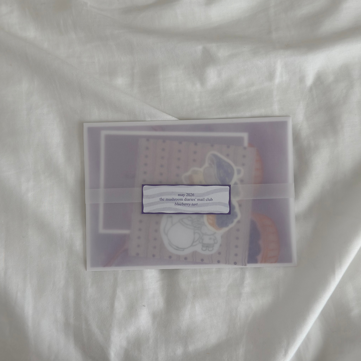purple themed snail mail inside a vellum paper sleeve with journaling goodies inside