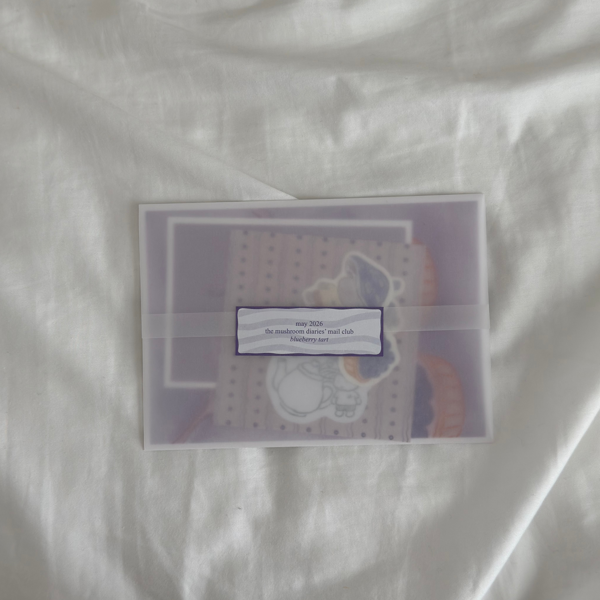 purple themed snail mail inside a vellum paper sleeve with journaling goodies inside